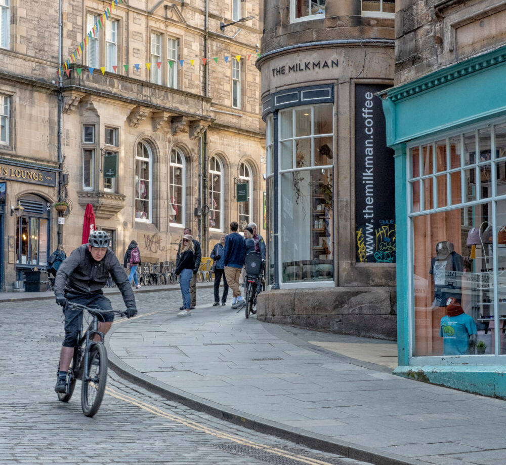Man cycling down a street in Edinburgh, Scotland