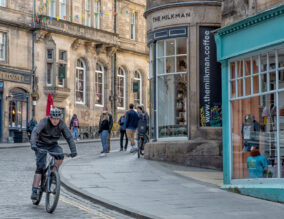 Man cycling down a street in Edinburgh, Scotland