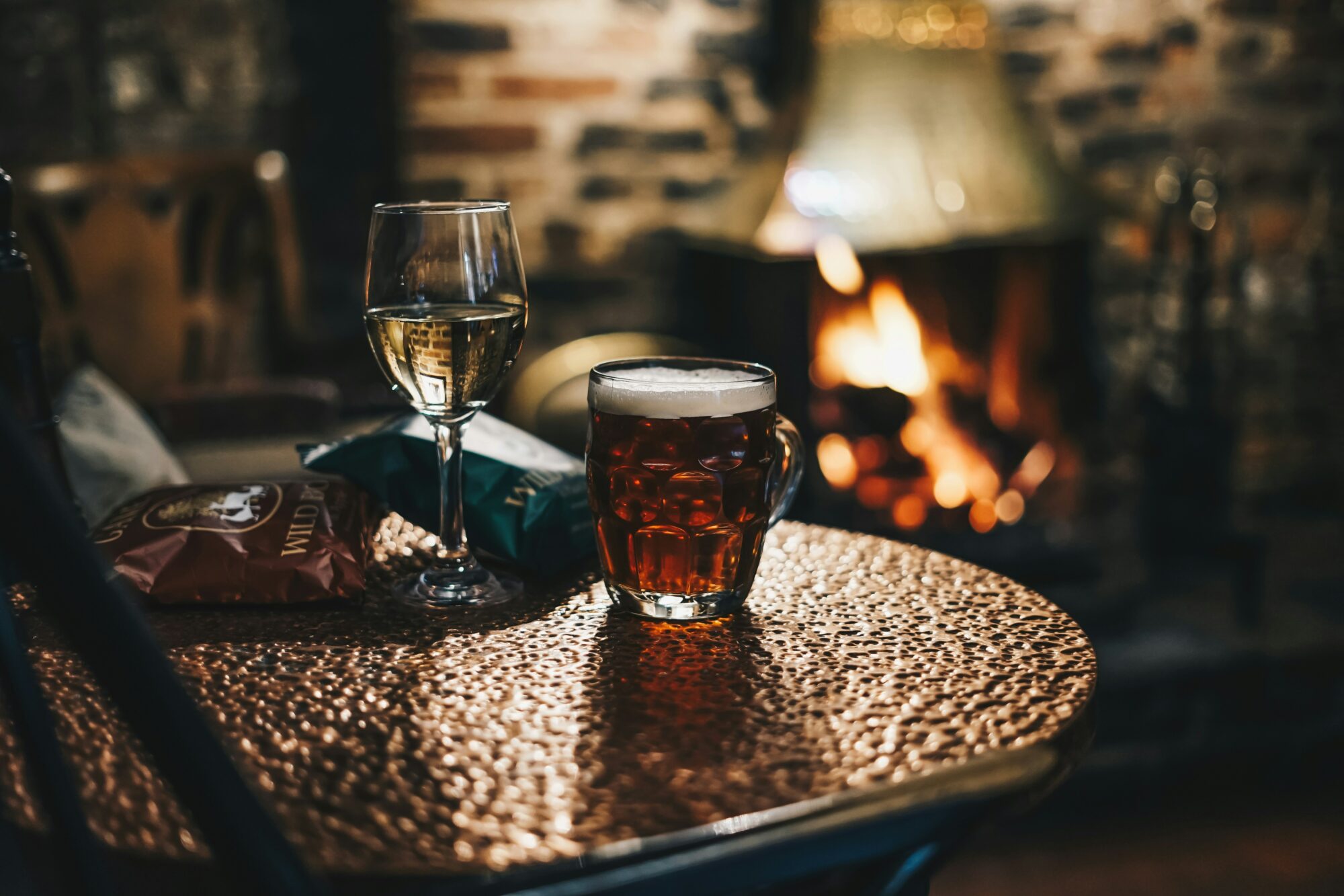 Glass of wine and pint of beer in a pub by the fire