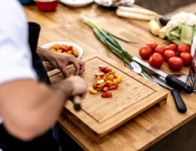 Chef in a kitchen chopping tomatoes